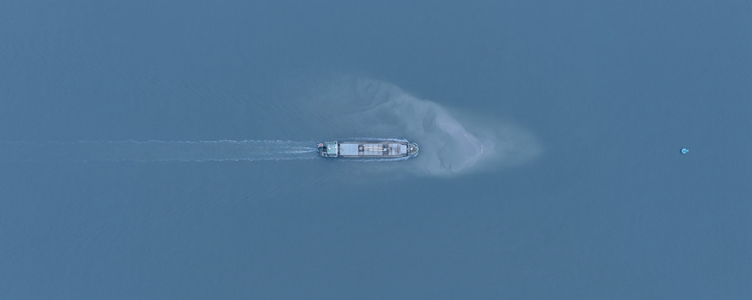 From above, a small ship on a straight course toward a sandbank just under the surface